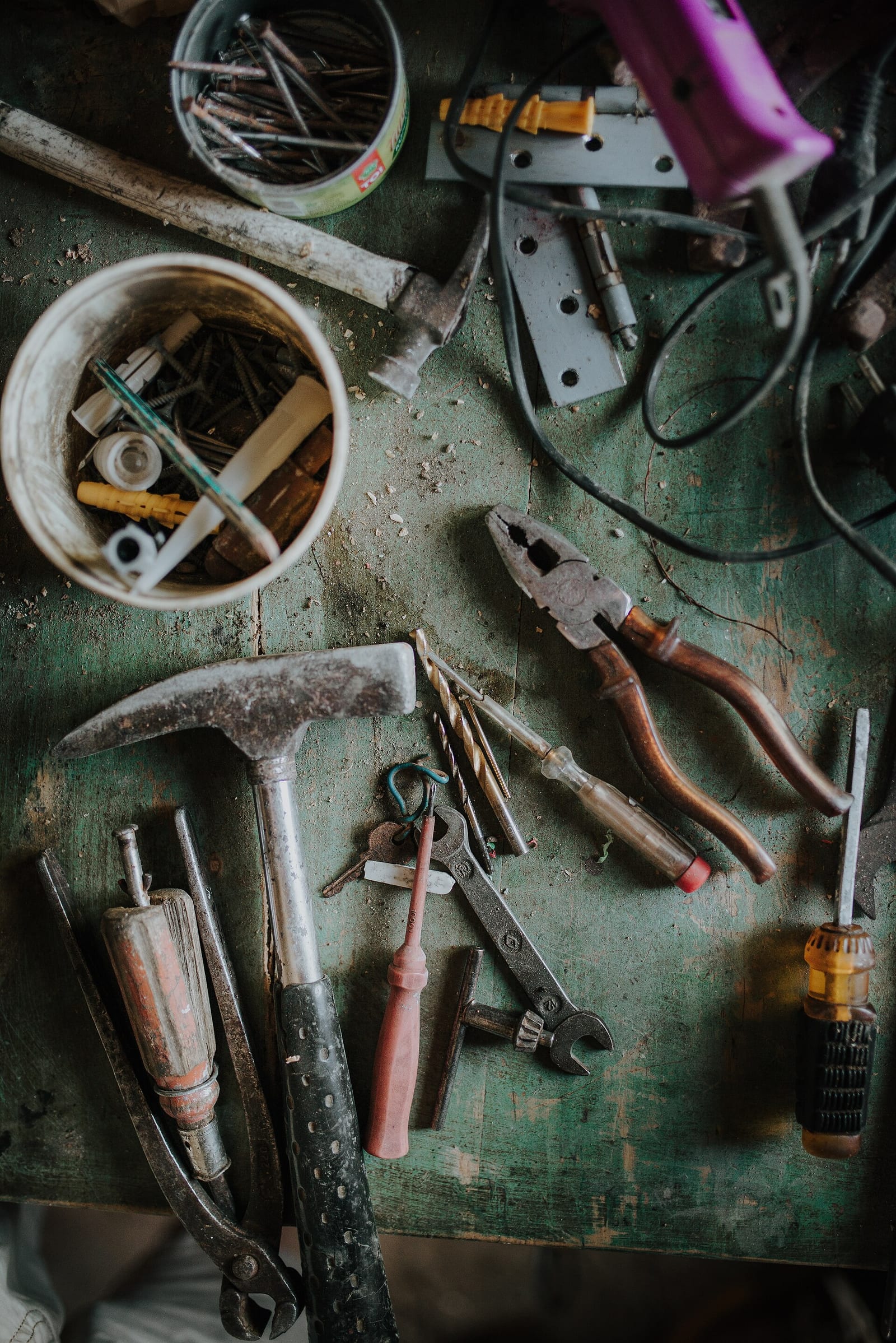 Hand tools and hardware on a green workbench